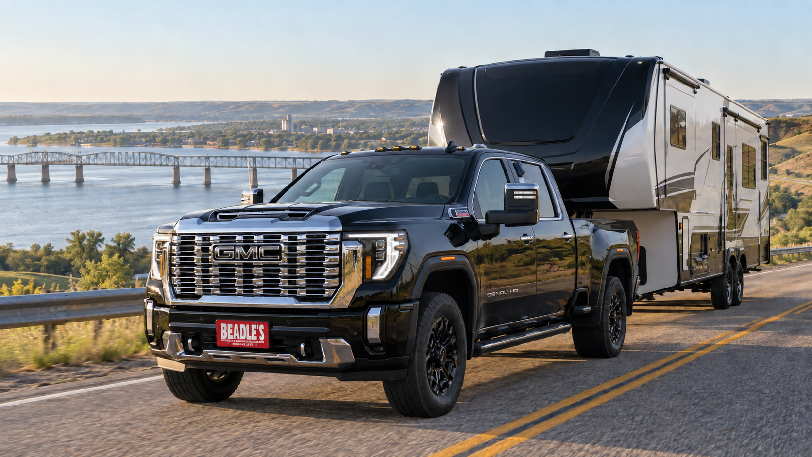 Onyx Black 2026 GMC Sierra 3500 HD Denali single rear wheel towing a large fifth-wheel on US 12 by the Missouri River bridge near Mobridge, South Dakota