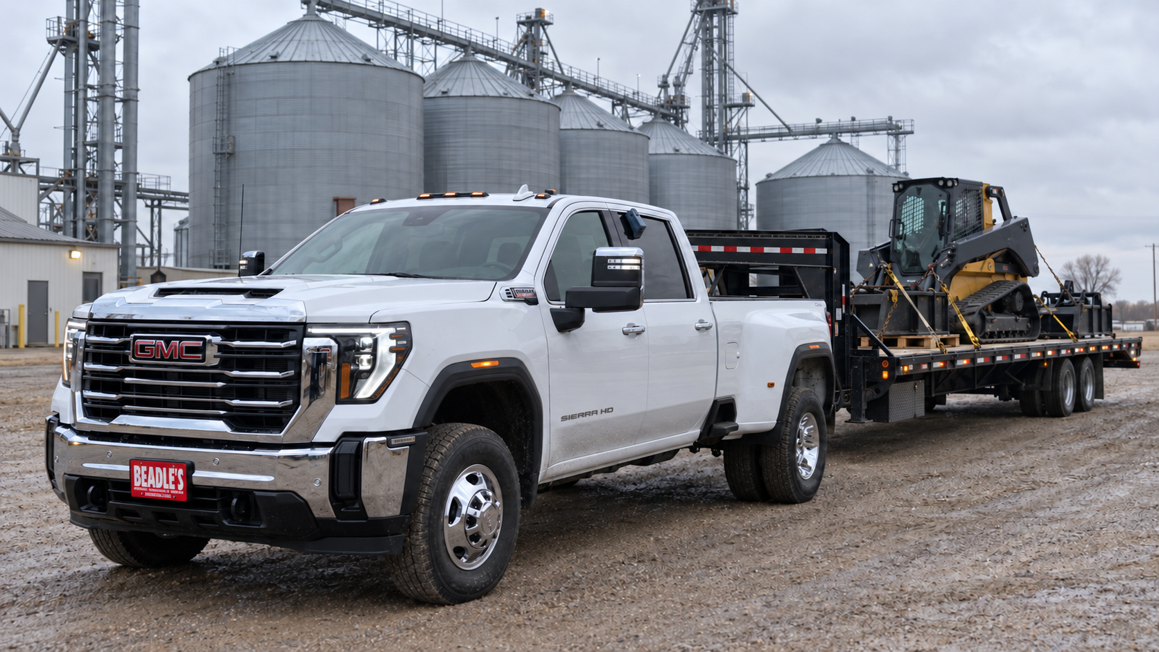 2026 GMC Sierra 3500 HD SLE dually backing a gooseneck hotshot deck loaded with a skid steer to a grain elevator dock near Mobridge, South Dakota