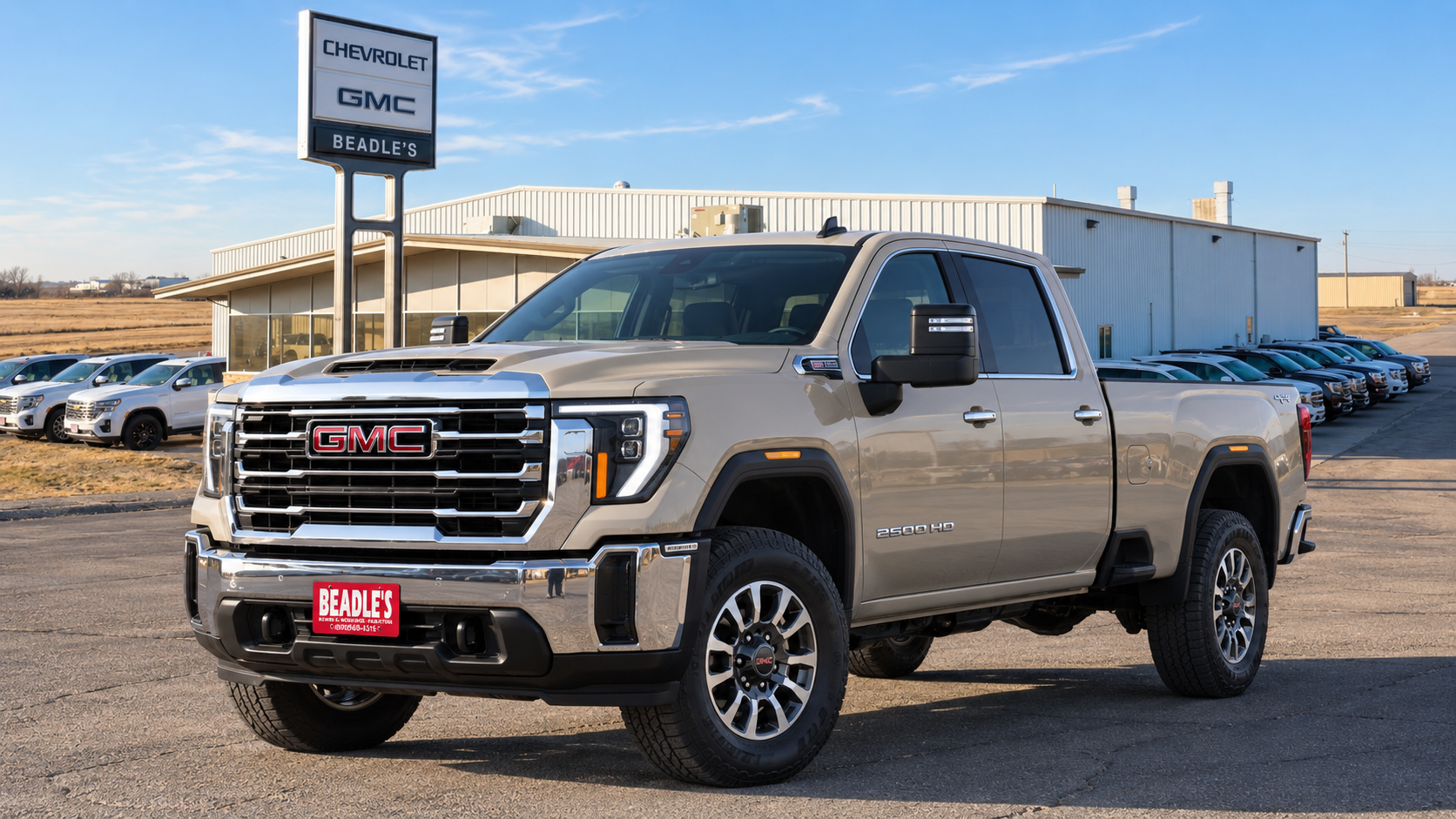 Coastal Dune 2027 GMC Sierra 2500 HD SLE on its standard 18-inch wheels parked in front of the showroom at Beadle Chevrolet GMC in Mobridge