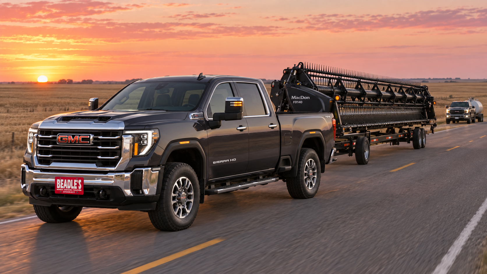 2027 GMC Sierra 2500 HD SLT long bed in Titanium Rush Metallic pulling a combine header trailer at dawn on a gravel road near Mobridge, South Dakota